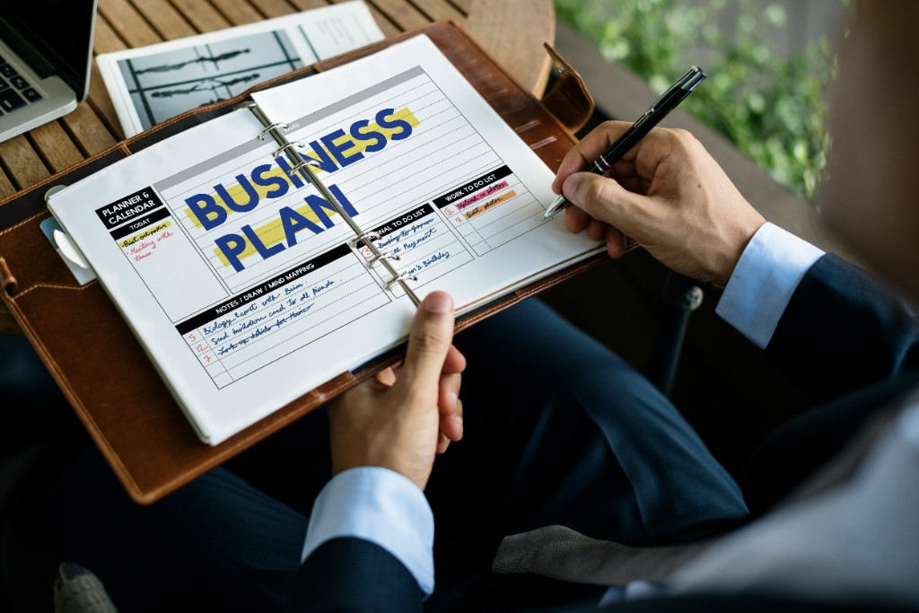 Person reviewing a handwritten business plan notebook