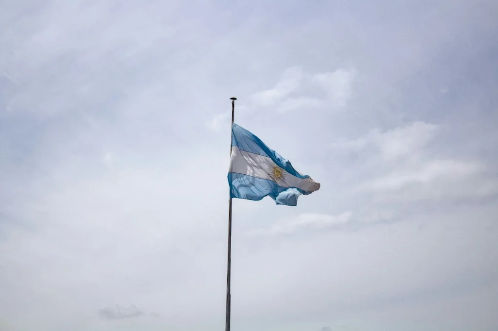Argentine flag flying from a pole against a cloudy sky