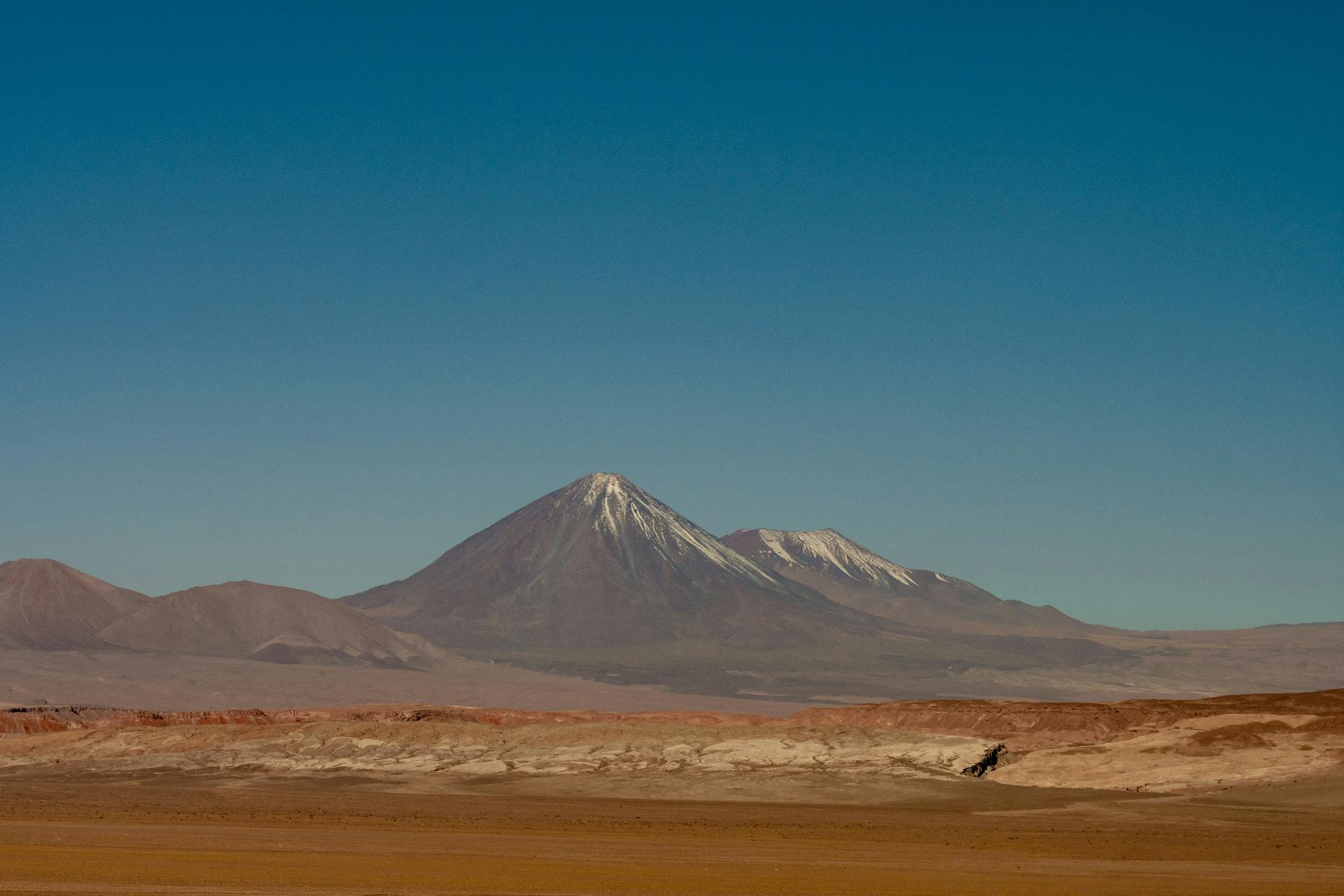 Snow-capped volcano over an Andean desert landscape