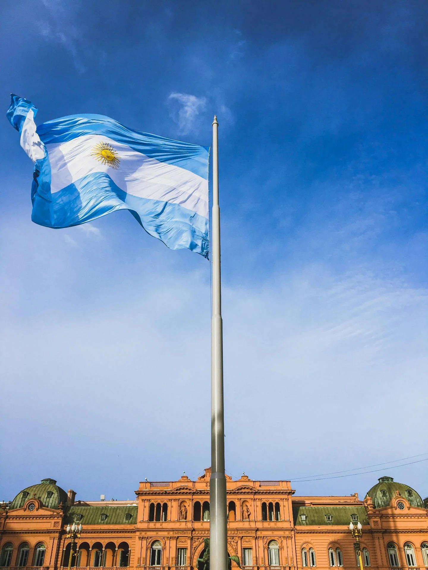 Argentine flag above Casa Rosada against a blue sky